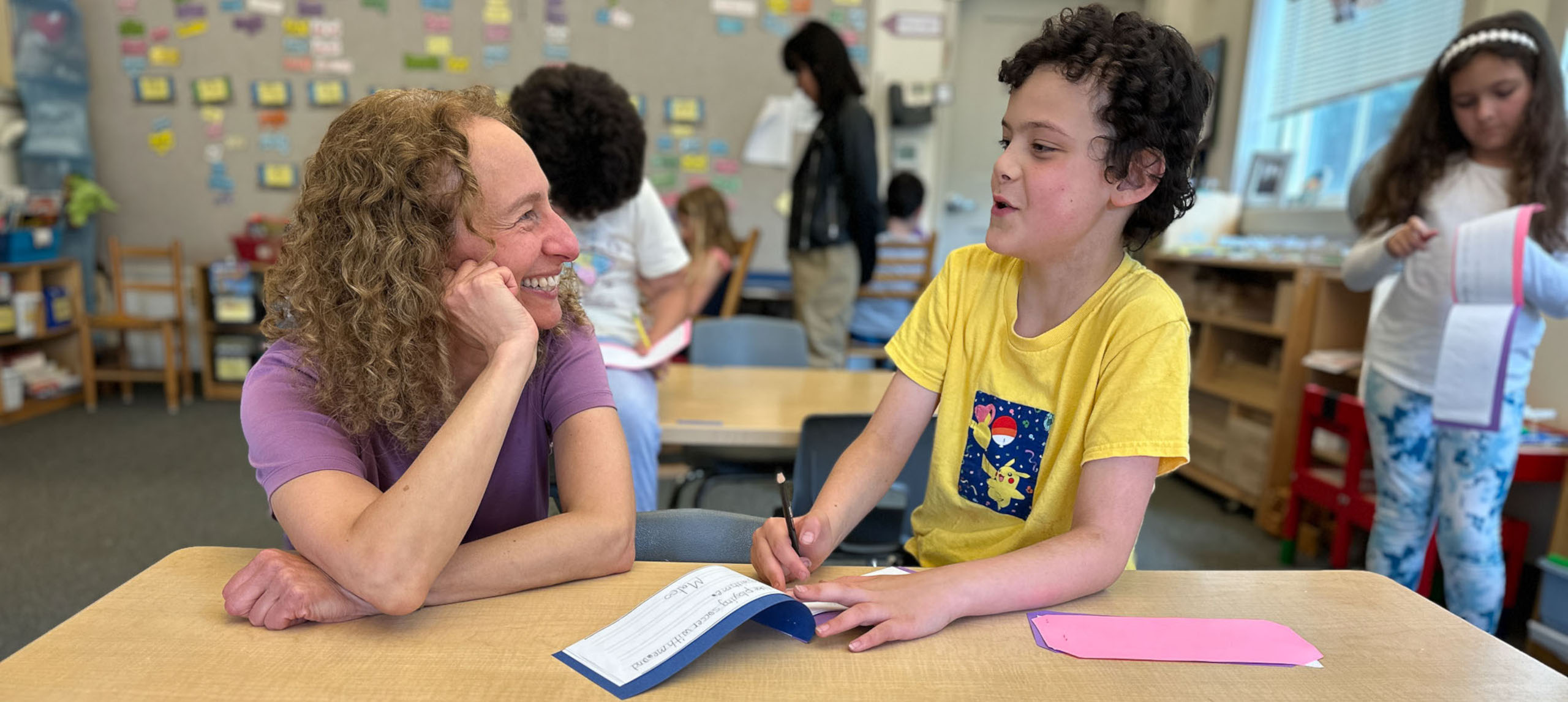 Student and teacher chatting at desk